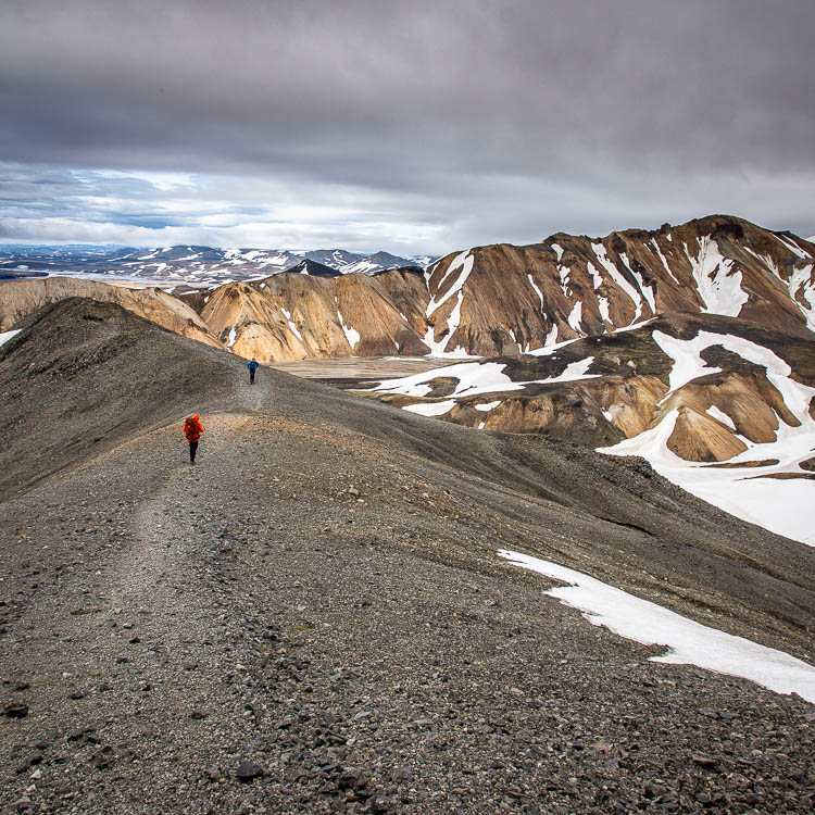 Deux randonneurs sur une crête de cendres, la trace filant vers les sommets