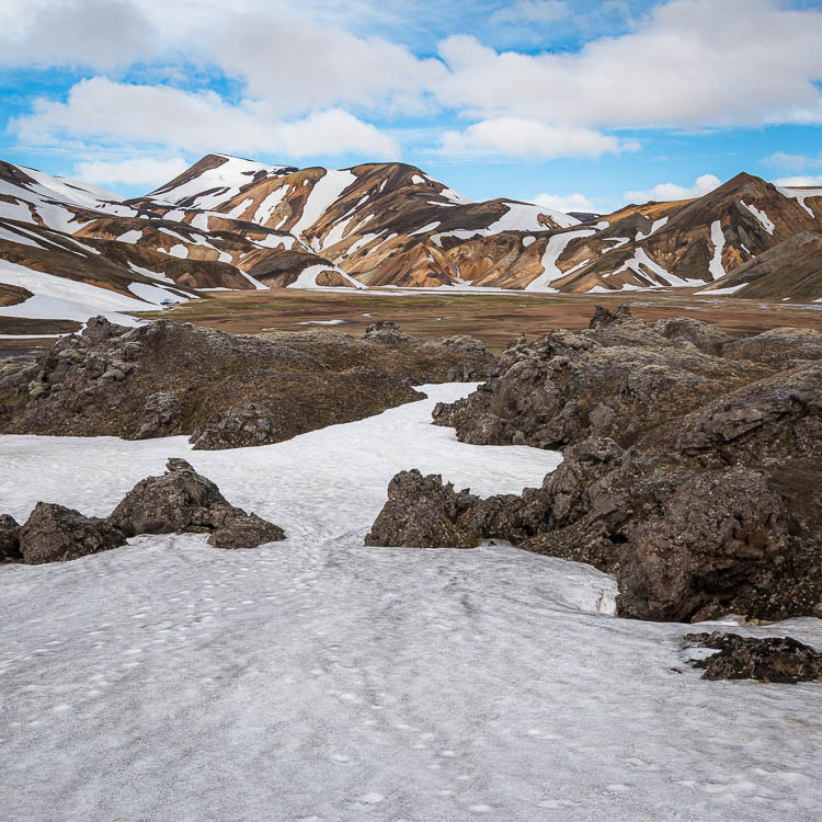 Névé traversant la coulée de lave de Laugahraun, montagnes enneigées au fond
