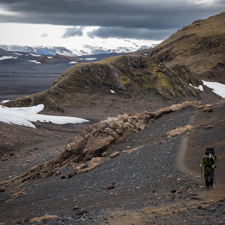 Randonneur solitaire sur le sentier, entre arête rocheuse et névés