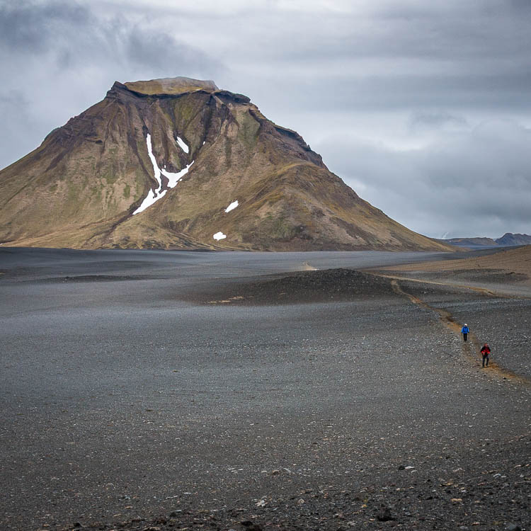 Montagne isolée dominant un vaste désert de sable volcanique noir