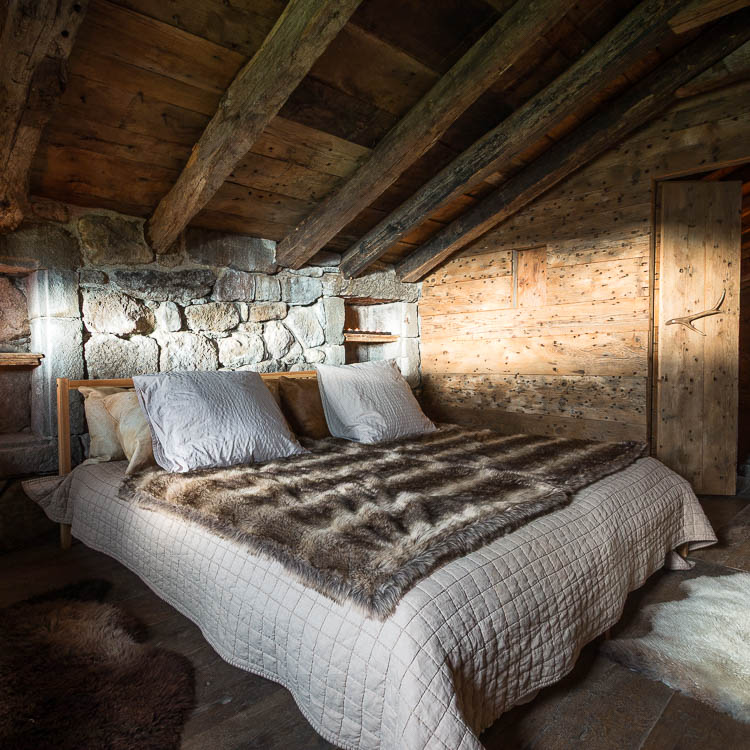 Chambre sous charpente du buron, mur de pierre et poutres anciennes
