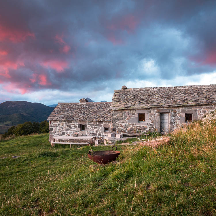 Le buron de la Chambe au couchant, ciel rose sur les monts du Cantal